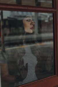 Pensive woman gazes through window, capturing nostalgic mood in Istanbul.